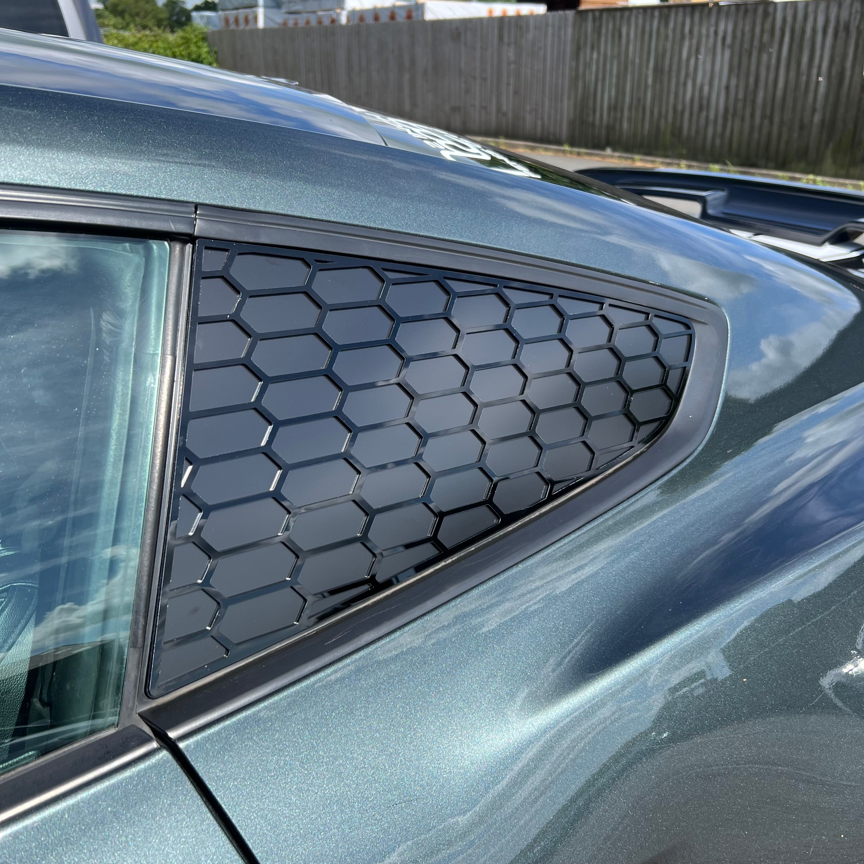Car window with honeycomb sunshade against a blurred outdoor background