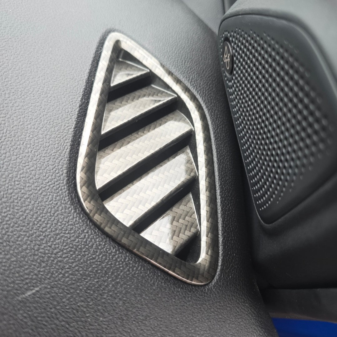 Car air vent with carbon fiber pattern on a gray dashboard